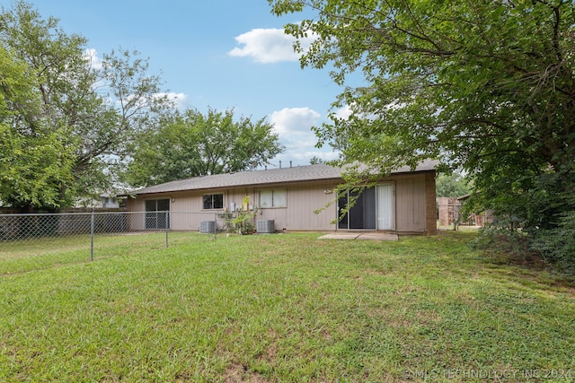 rear view of property with cooling unit and a lawn