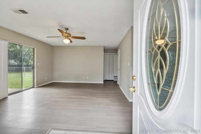 foyer featuring hardwood / wood-style flooring, ceiling fan, and a textured ceiling