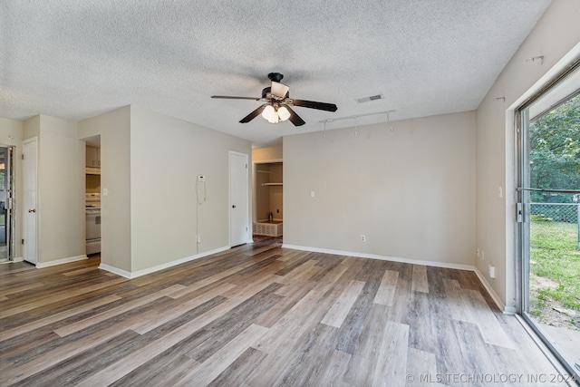 empty room featuring ceiling fan, hardwood / wood-style flooring, rail lighting, and a textured ceiling