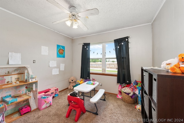 playroom featuring ceiling fan, ornamental molding, carpet flooring, and a textured ceiling