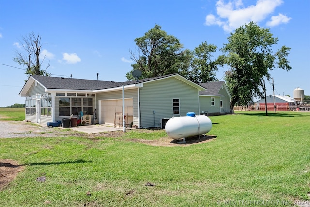 rear view of property with a garage and a lawn