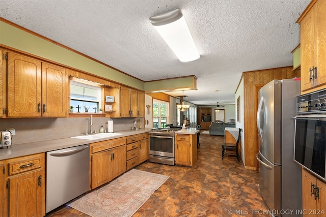 kitchen featuring sink, crown molding, hanging light fixtures, appliances with stainless steel finishes, and kitchen peninsula