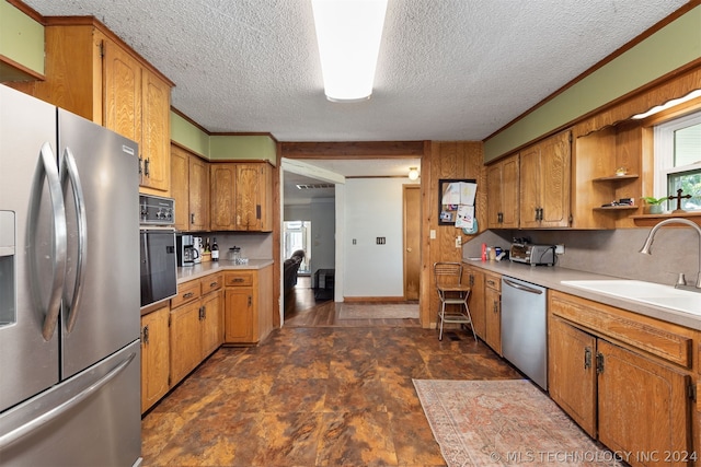 kitchen with sink, decorative backsplash, ornamental molding, stainless steel appliances, and a textured ceiling