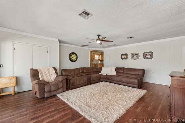 living room with dark hardwood / wood-style floors, wood walls, ornamental molding, ceiling fan, and a textured ceiling