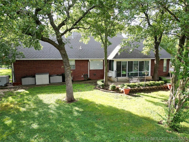 rear view of house with a yard, a patio area, and a sunroom