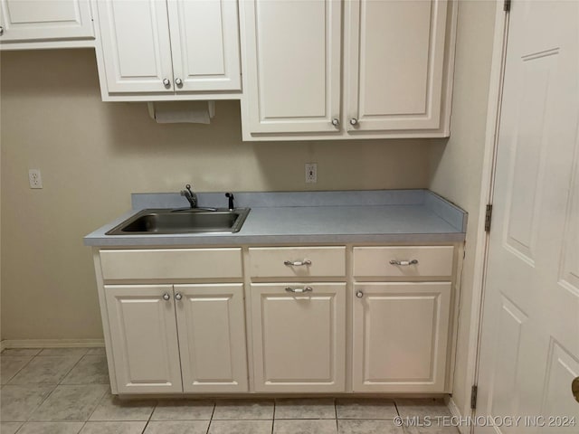 kitchen featuring sink, light tile patterned floors, and white cabinets