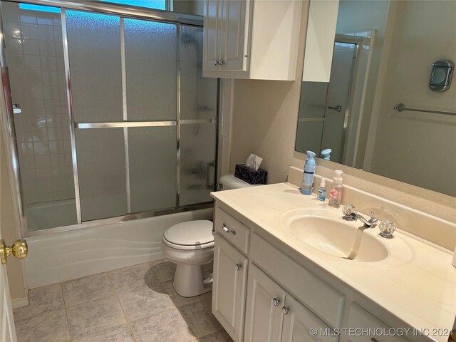 full bathroom featuring tile patterned flooring, vanity, toilet, and combined bath / shower with glass door