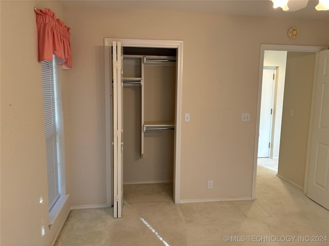 unfurnished bedroom with light colored carpet and a closet