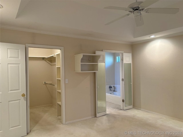 unfurnished bedroom featuring a spacious closet, light carpet, ornamental molding, a closet, and ceiling fan