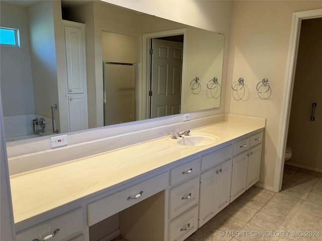 bathroom featuring vanity, an enclosed shower, tile patterned flooring, and toilet