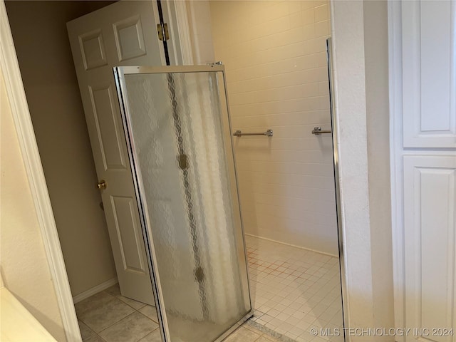 bathroom with an enclosed shower and tile patterned flooring