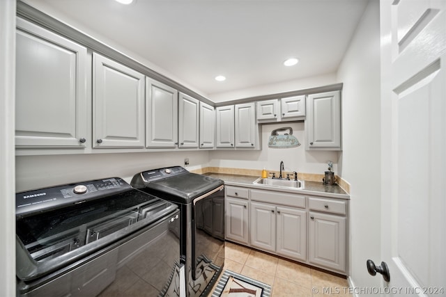 laundry area featuring sink, light tile patterned floors, cabinets, and independent washer and dryer