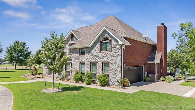 view of front facade featuring central air condition unit, a front yard, and a garage