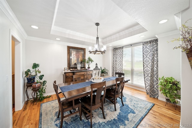 dining area with crown molding, a tray ceiling, and light hardwood / wood-style flooring