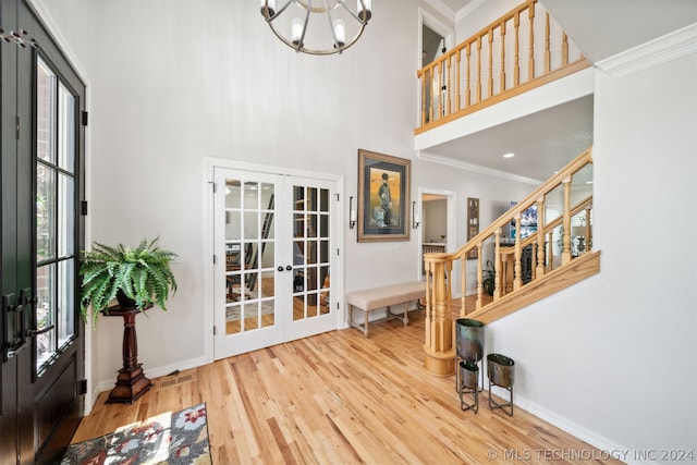 entrance foyer with hardwood / wood-style flooring, french doors, a wealth of natural light, and ornamental molding