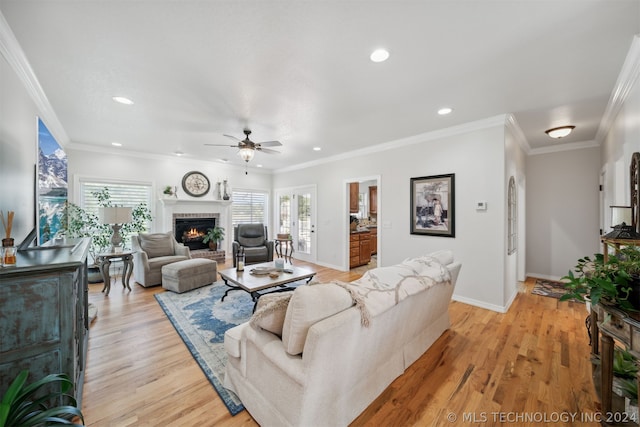 living room with a fireplace, light wood-type flooring, ceiling fan, and ornamental molding