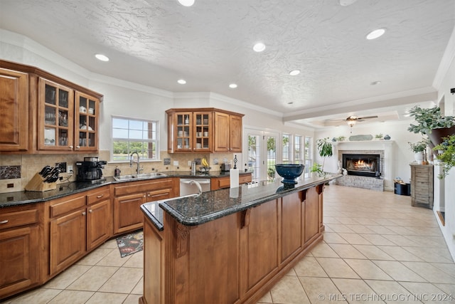 kitchen featuring stainless steel dishwasher, a center island, a breakfast bar area, dark stone countertops, and sink