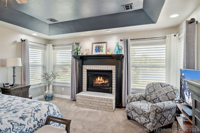 bedroom featuring carpet, ceiling fan, a tray ceiling, and a fireplace