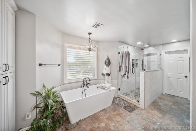 bathroom with independent shower and bath and an inviting chandelier