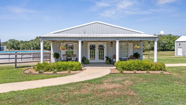 view of front of home with french doors, a front yard, and a fenced in pool