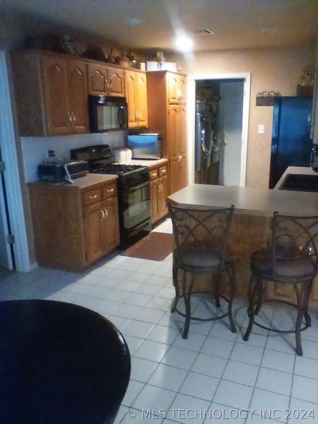 kitchen with black appliances, light tile patterned floors, and sink