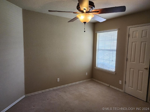 carpeted spare room with plenty of natural light and ceiling fan