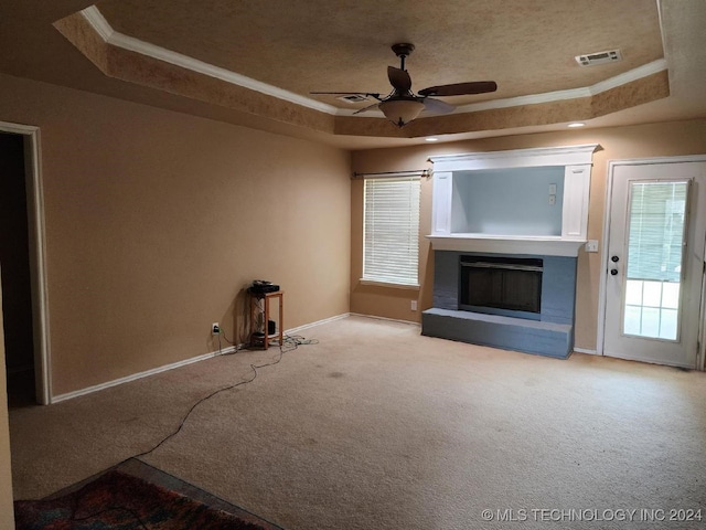 unfurnished living room featuring ceiling fan, a raised ceiling, carpet floors, and crown molding