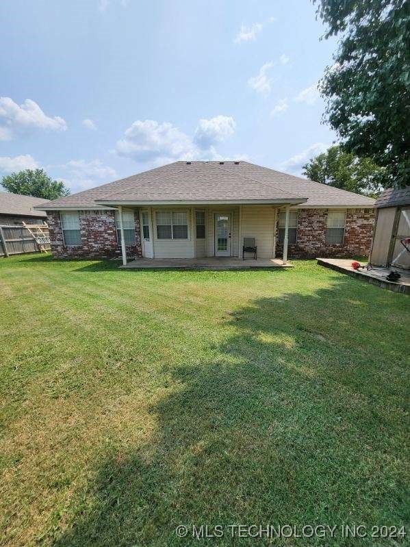 rear view of house featuring a patio, a yard, and a shed