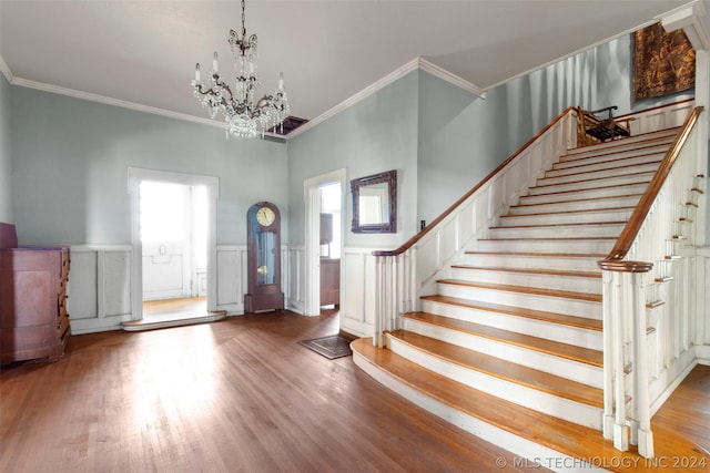 entryway featuring hardwood / wood-style flooring, plenty of natural light, ornamental molding, and a chandelier