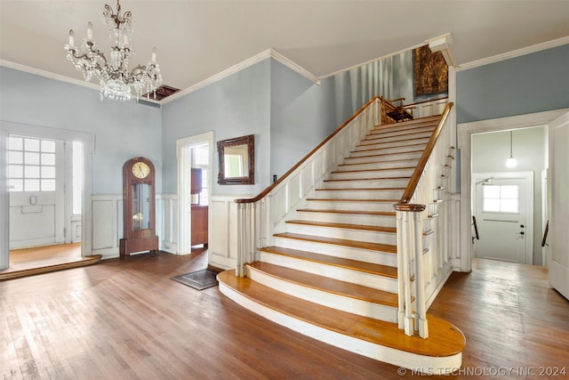 entryway with hardwood / wood-style flooring, crown molding, and an inviting chandelier