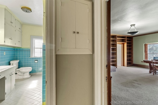 bathroom with a wealth of natural light, crown molding, vanity, and toilet