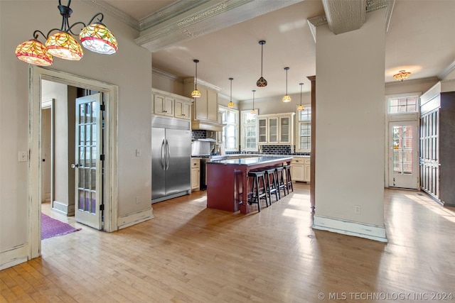 kitchen with a kitchen breakfast bar, light wood-type flooring, a kitchen island, pendant lighting, and built in refrigerator