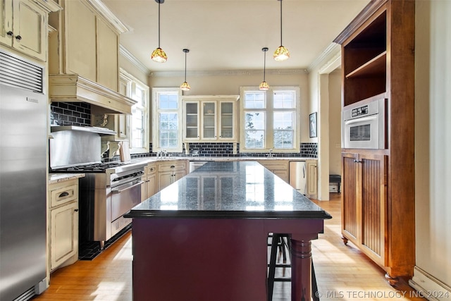 kitchen with a center island, high end appliances, a healthy amount of sunlight, and hanging light fixtures