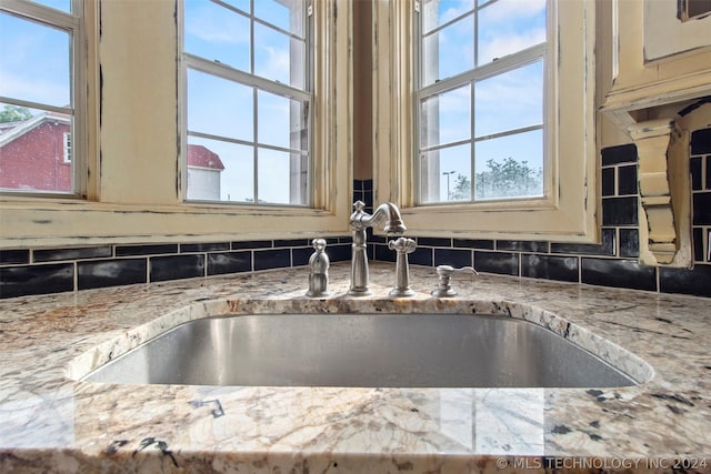 details featuring light stone countertops, cream cabinets, backsplash, and sink