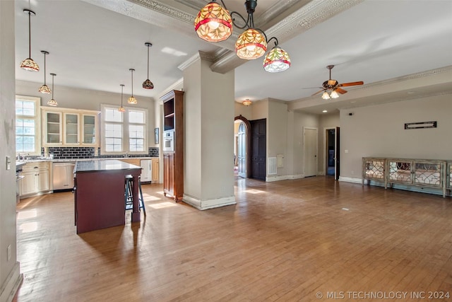 kitchen featuring dishwasher, crown molding, pendant lighting, a breakfast bar area, and a kitchen island