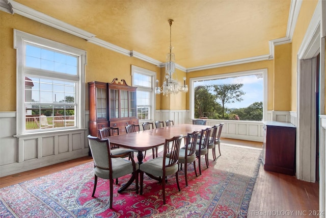 dining space with hardwood / wood-style floors, an inviting chandelier, and ornamental molding