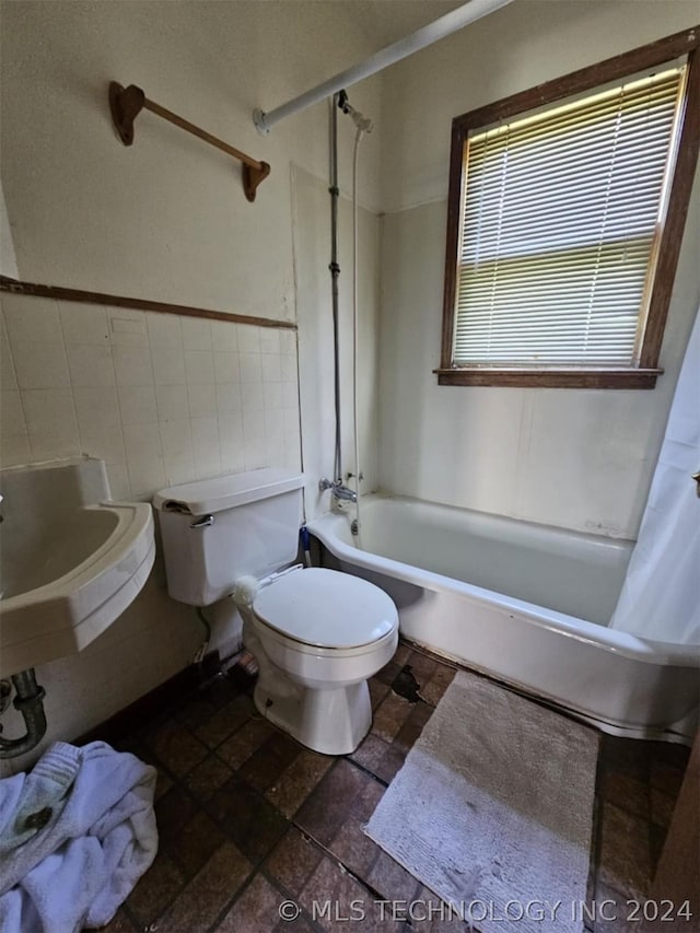 303 S B, Davis, OK 73030 - bathroom featuring tile walls, toilet, shower / bathtub combination with curtain, stone tile flooring, and a sink