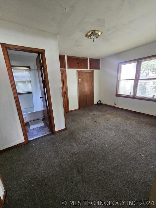 303 S B, Davis, OK 73030 - unfurnished bedroom with baseboards and dark carpet