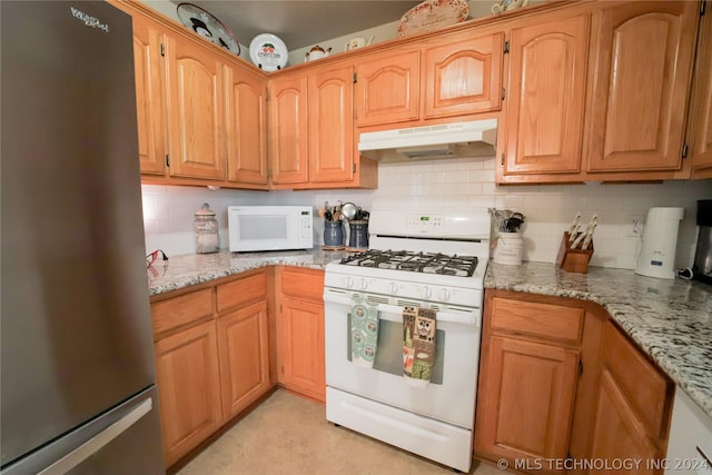 kitchen featuring white appliances, light stone counters, and backsplash