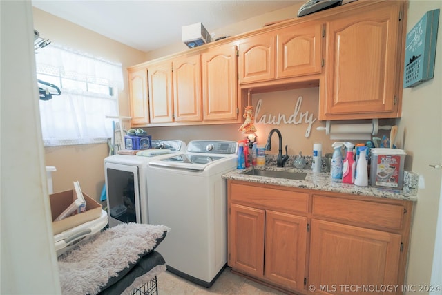 laundry area featuring washing machine and clothes dryer, sink, and cabinets