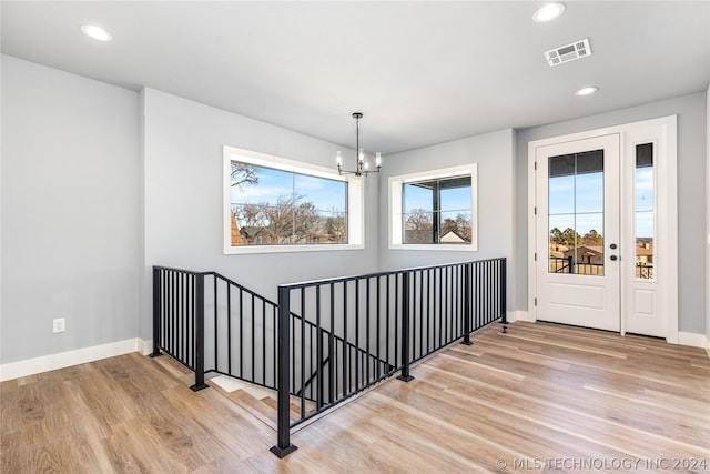 stairs with hardwood / wood-style flooring and a notable chandelier