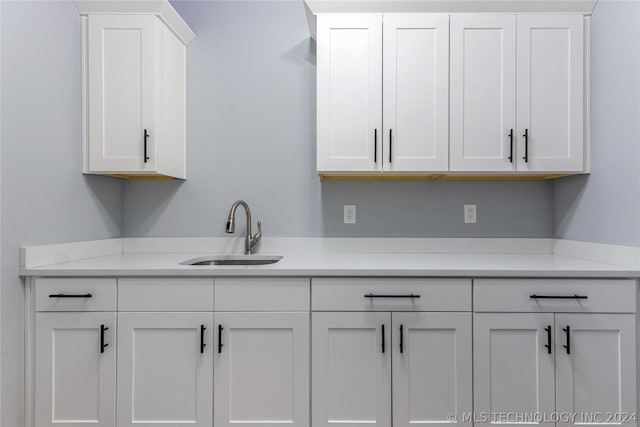 kitchen with light countertops, a sink, and white cabinetry