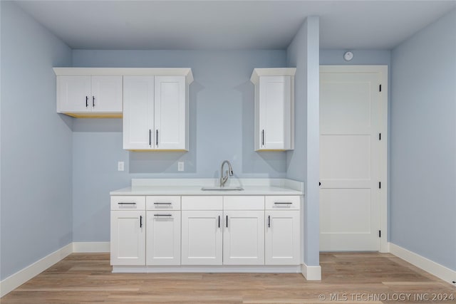 kitchen featuring a sink, light countertops, white cabinets, and light wood-style floors