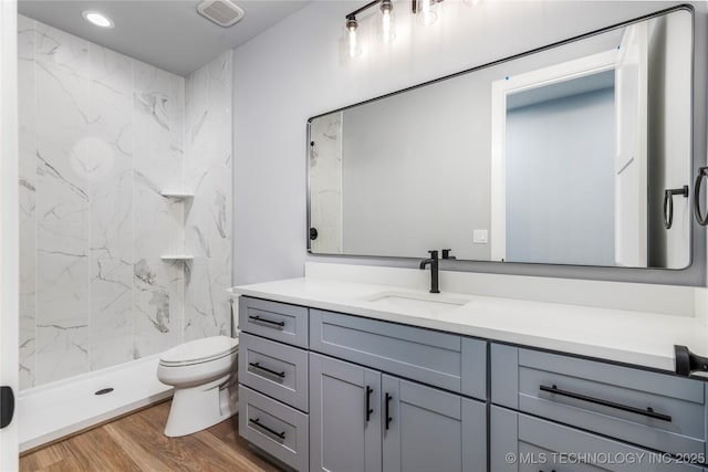 bathroom with vanity, visible vents, toilet, wood finished floors, and a marble finish shower