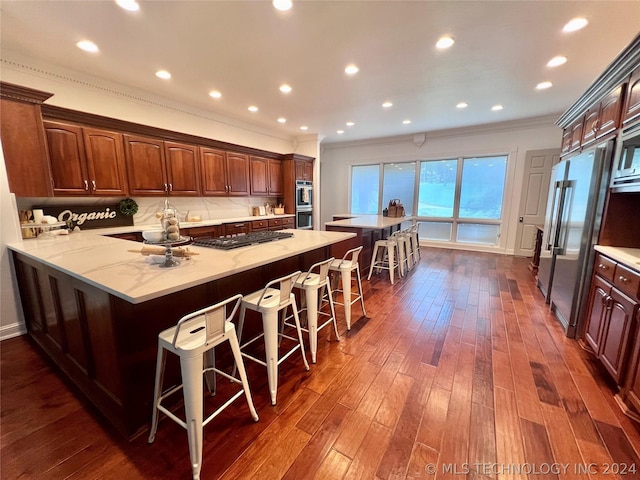 kitchen with a kitchen breakfast bar, dark hardwood / wood-style floors, kitchen peninsula, and appliances with stainless steel finishes