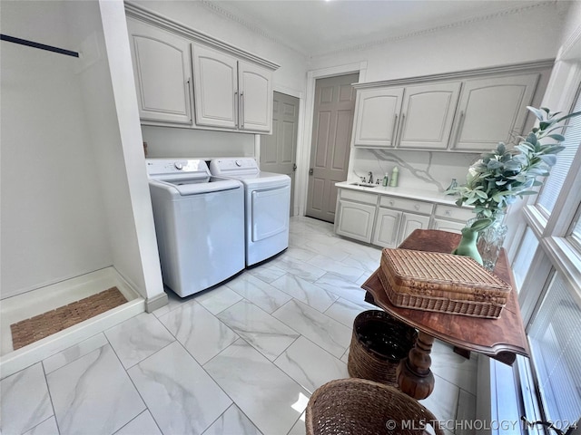 laundry room featuring cabinets, washing machine and clothes dryer, and ornamental molding