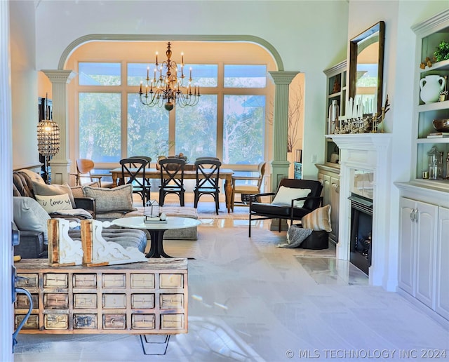 living room with a chandelier, decorative columns, a premium fireplace, and a healthy amount of sunlight