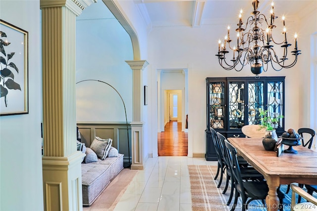 dining area with decorative columns, light tile patterned floors, and beamed ceiling