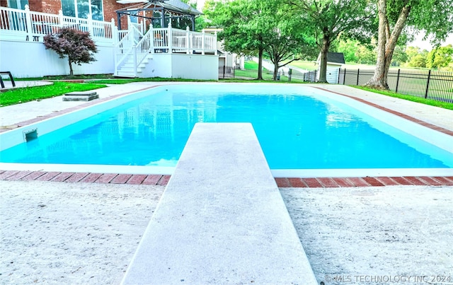 view of swimming pool featuring a wooden deck and a diving board