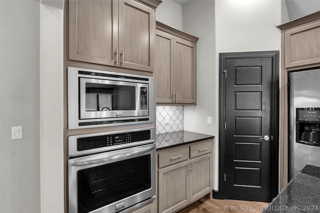 kitchen with appliances with stainless steel finishes, hardwood / wood-style flooring, and backsplash